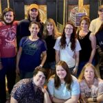 A group of people in front of axe throwing bays